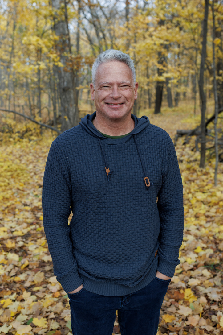 John Belman standing outdoors in an autumn woodland